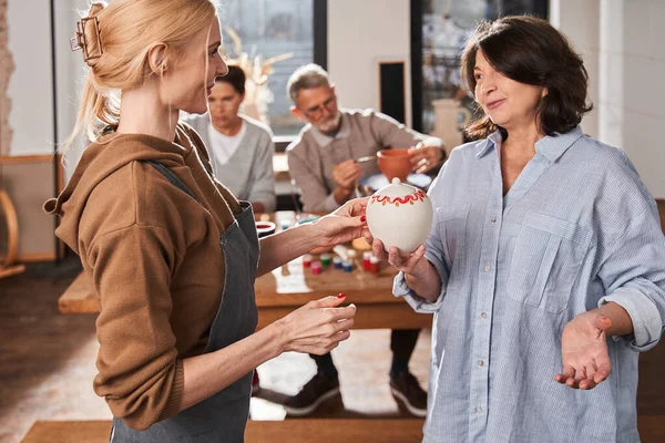 Senior woman giving hand made clay pot to her teacher after the master class — Fotografia de Stock