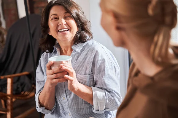 Genç öğretmeniyle gülen ve kahve içerken onu dinleyen bir kadın.