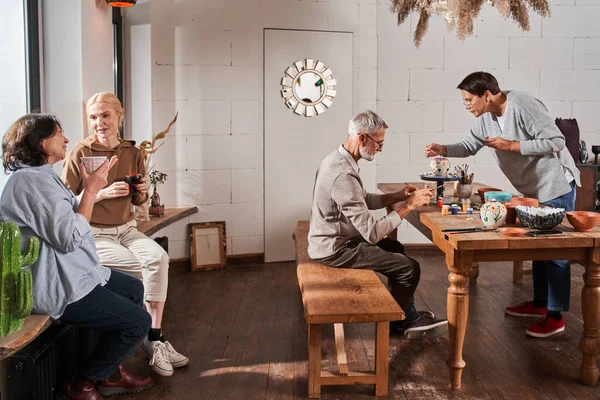 Masada oturan ve el yapımı çaydanlıklar yapan iki emekli.