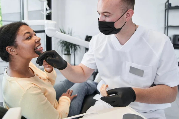 I need check your bite. Confident doctor in protective equipment making check up of his female patient before the whitening procedure. Stock photo