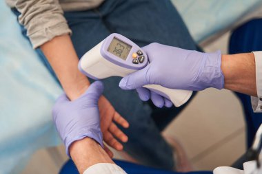 Çocuk doktorunun, aile doktorlarının ofisindeki küçük kızların vücut ısılarını modern temas kurulamayan dijital termometreyle ölçtüğü görüntüler.