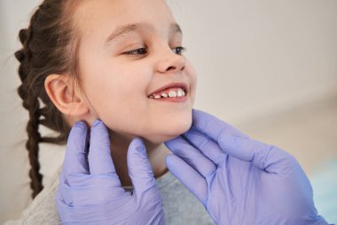 Klinikte liseli kızın boğazını sıkan koruyucu eldivenler giyen erkek doktorun görüntüsü. Soğuk algınlığı, koronavirüs, çocuk konseptinde bademcik iltihabı.