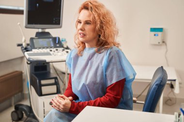 Ciddi bir beyaz kadın doktoruna sağlığıyla ilgili bir şeyler söylüyor. Sakin kadın hasta hastanede sohbet ediyor. Stok fotoğrafı