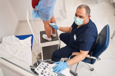 Kadın modern teknoloji kliniğinde ultrason sensörü üzerinde tıbbi muayeneden geçiyor. Damarların durumu ve doppler inceleniyor.