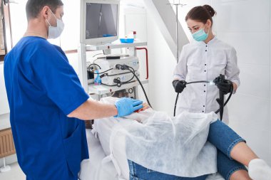 Klinikteki endoskopi sırasında doktor ve hemşire. Modern klinikteki gastroskopiden önce hastasını sakinleştiren konsantre bir adam.
