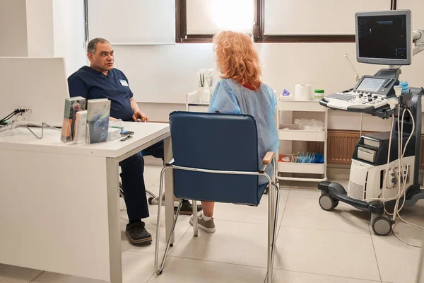 Yaşlı erkek doktor hastanede kadın hastaya danışıyor. Kıdemli pratisyen hekim ya da terapist kadın müşteriyle özel klinikte görüşüyor. İyi bir sağlık hizmeti. Sağlık ve Tıp Konsepti