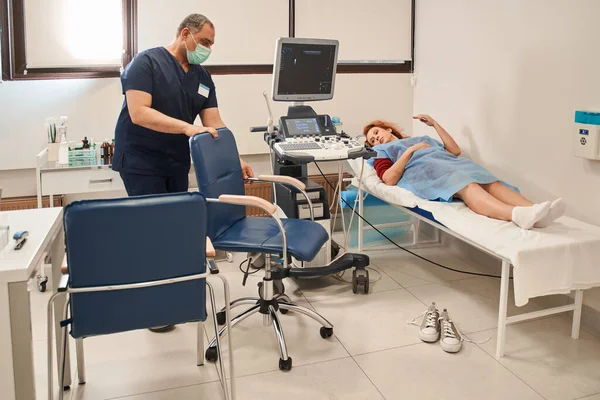 Kıdemli doktor hastanede kadınların karnına ultrason yapmaya hazırlanıyor. Erkek doktor hastasının iç organlarının ultra sesini çıkarıyor.