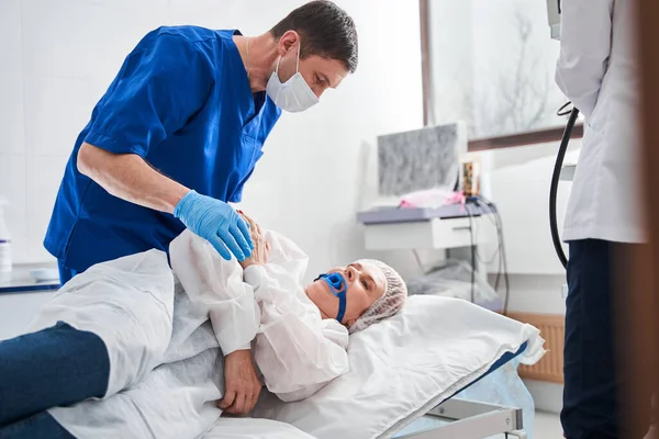 大腸内視鏡前の病院のベッドで患者さんと話をしている医師の長距離ビュー — ストック写真