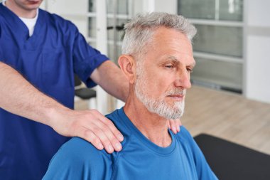 Cropped view of the senior patient sitting during the massage session while sitting at the bench. Recovery at the retirement age concept