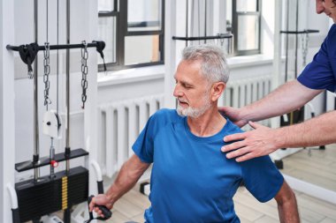 Skilful physiotherapist working with mature patient in clinic office. Recovery and rehabilitation after injury concept. Stock photo