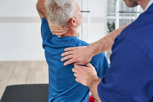 Rehabilitation Therapist Stretching Arm Back Elderly Man Physical Therapy Hospital — Foto Stock