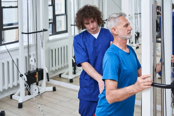 Medical specialist working on mature mans mobility of his back. Physiotherapy and rehabilitation of mature adult male. Stretching and pressure release concept