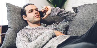 Gülümseyen mutlu yaratıcı adamın portresi dijital teknoloji akıllı telefonu kullanarak rahatlıyor. Genç adam arayıp arkadaşlarıyla konuşuyor.