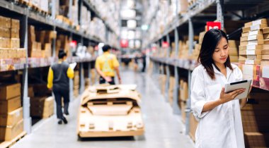 Asyalı bir kadının portresi, dağıtım endüstrisi deposunda ürün geçmişi olan raflardaki ürün ve erzakları kontrol etmek için tabletin detaylarını sipariş ediyor. Lojistik ve iş dünyası.