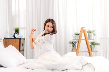 Gülümseyen, güzel, güzel Asyalı bir kadının portresi temiz, sağlıklı, beyaz tenli, pijamalı, beyaz elbiseli bir kız.