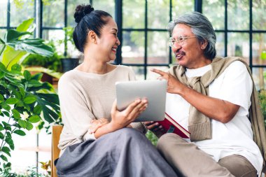 Üst düzey Asyalı çift tablet bilgisayarlarını birlikte kullanırken iyi vakit geçiriyor. Mutlu yaşlı karı koca sosyal medyayı kontrol ediyor, haberleri okuyor ya da evde otururken internetten alışveriş yapıyor.