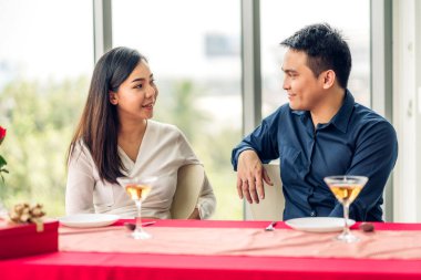 Romantik genç Asyalı mutlu aşk çifti. Birlikte rahatlıyor ve sohbet ediyorlar. Akşam yemeği partisinde şarap bardakları içiyorlar.