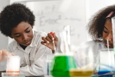 İki Afro-Amerikan tatlı oğlan ve kız öğrenci araştırma öğreniyor ve kimyasal deney yapıyor. Fen dersinde test tüpünde sıvı karıştırıyor ve analiz ediyor.