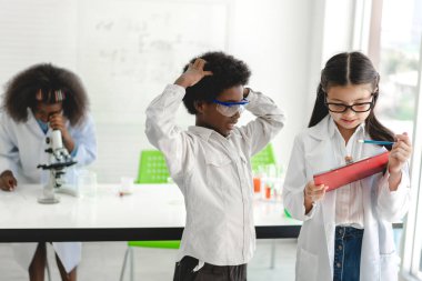 Okuldaki deney laboratuarında test tüpünde sıvı karıştırıp analiz ederken araştırma yapmayı ve kimyasal deney yapmayı öğrenen bir grup küçük tatlı öğrenci. Eğitim.