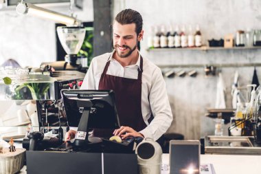 Yakışıklı sakallı baristanın portresi. Küçük işletme sahibi. Kafenin arkasında bilgisayarla çalışıyor.