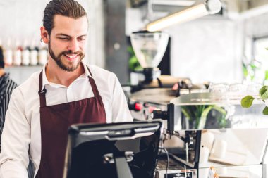 Yakışıklı sakallı baristanın portresi. Küçük işletme sahibi. Kafenin arkasında bilgisayarla çalışıyor.