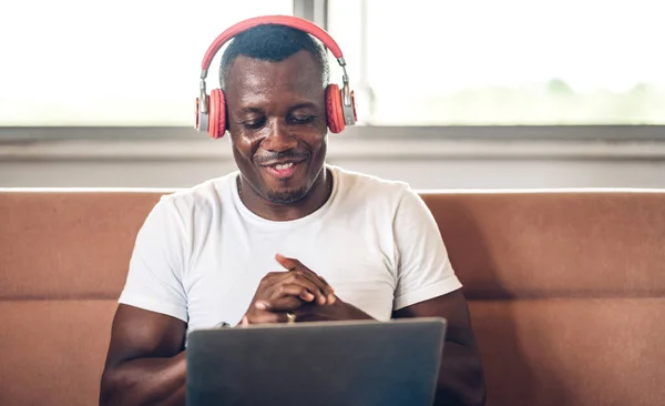 Young black african man relaxing using laptop computer working and video conference meeting at home.Young creative african man talk with headset.work from home concept