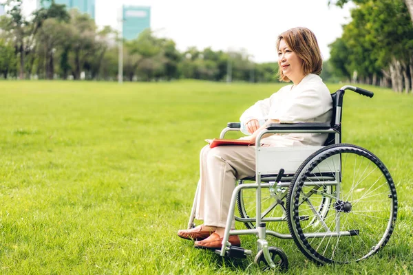 Yaşlı Yaşlı Asyalı Kadınlar Tekerlekli Sandalyeye Oturup Açık Havada Kitap — Stok fotoğraf