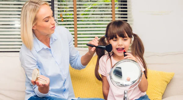 Portrait of enjoy happy love family mother with little daughter having fun and holding make-up brushes and make up on face with cosmetic set together on the sofa at home.Love of family and concept