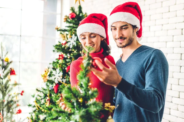 サンタの帽子のロマンチックな甘いカップルは クリスマスツリーを飾る楽しさと笑顔を楽しみながら 新年の前夜を祝い 自宅でクリスマスの時間に一緒に過ごすことを楽しむ — ストック写真