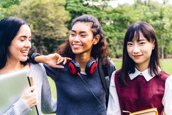 笑顔の女子留学生やティーンエイジャーが立ち上がり 大学の公園で学生のグループとカメラを見て本を保持します 教育と友情コンセプト — ストック写真