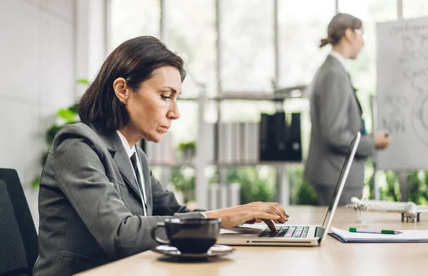 Portrait of businesswoman relax work and looking at technology of laptop computer sitting on chair.Young hipster girl business thinking with new idea at office