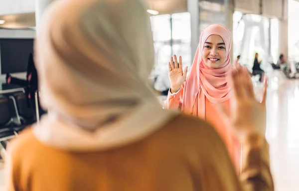 Two young friend beauty islamic asian arabic muslim woman wearing a hijab enjoying and having fun talking together waving hi and saying hello in the shop at fashion store