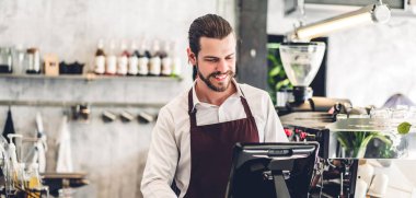 Yakışıklı sakallı baristanın portresi. Küçük işletme sahibi. Kafenin arkasında bilgisayarla çalışıyor.