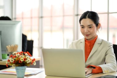 Ofis masasında otururken bilgisayarına bakan kendine güvenen güzel Asyalı iş kadını. Genç yaratıcı iş arkadaşları. Çalışan ve planlayan iş adamları.
