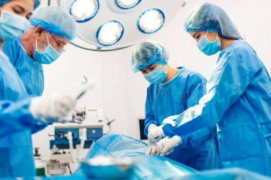 Profesyonel anestezi uzmanı doktor tıp ekibi ve asistanı modern hastane acil servisinde cerrahi ekipmanla jinekolojik ameliyata hazırlanıyor.