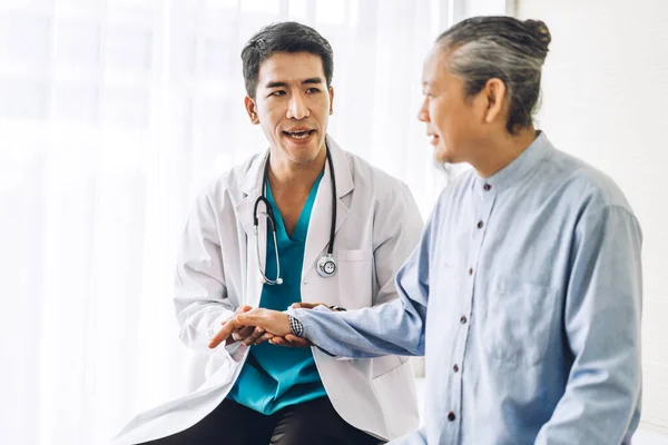 Asian man doctor wearing uniform with stethoscope help support discussing and holding hand asian senior man patient reassuring with trust care in hospital.healthcare and medicine