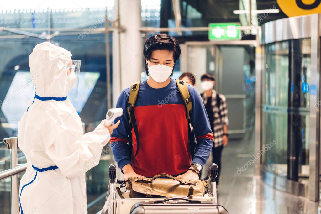 Doctor woman use infrared forehead thermometer for check body temperature scan travel passenger fever in quarantine for coronavirus omicron wearing safety mask at International terminal airport	