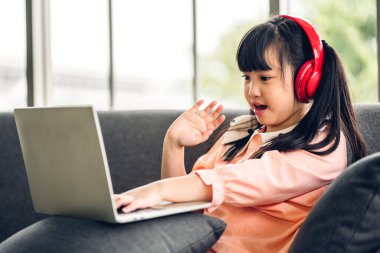 Öğrenci küçük kız öğreniyor ve dizüstü bilgisayara bakıyor ev ödevi yapıyor çevrimiçi eğitim sistemi ile bilgi öğreniyor. Evde öğretmenle çocuk video konferansı