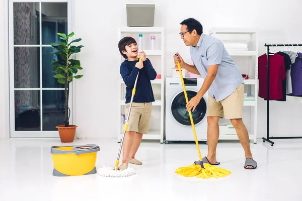 爸爸教亚洲小孩 小男孩在家里一起打扫房子的时候 一边做家务活 一边擦地板 一边用扫帚擦灰尘 玩得很开心 — 图库照片