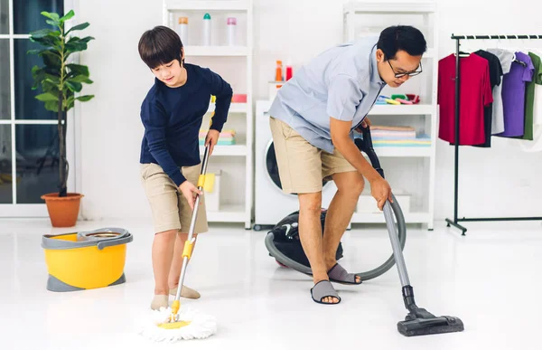 爸爸教亚洲小孩 小男孩在家里一起打扫房子的时候 一边做家务活 一边擦地板 一边用扫帚擦灰尘 玩得很开心 — 图库照片