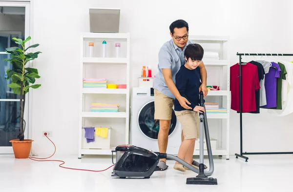 家庭で掃除をしたり 掃除機でほこりを拭いたりしながら家で一緒に掃除をしたりする家庭的な家事を楽しんでいるアジアの子供の男の子の息子を教える父 — ストック写真