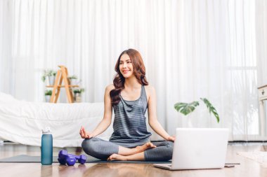 Portre sporu spor, spor kıyafetleri içinde ince kadın, rahatlama ve yoga yapan kız, yatak odasında dizüstü bilgisayarla spor yapıyor. Diyet konsepti. Fitness ve sağlıklı.