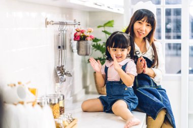 Mutlu aşk portresi. Asyalı anne ve küçük Asyalı kız çocuk gülümsüyor ve evde mutfakta birlikte kahvaltı hazırlıyorlar.