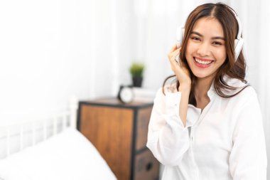 Gülümseyen, güzel, güzel Asyalı bir kadının portresi temiz, sağlıklı, beyaz tenli, pijamalı, beyaz elbiseli bir gülümseme. Düşen bir kız evde yatağında dinleniyor ve eğleniyor.