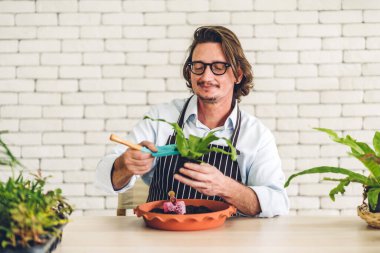 Mutlu bahçıvan kıdemli yaşlı adam bahçedeki küçük ağaçla ilgilenen çiçek sulama ve bahçeyle bahçeye bakıyor. Emeklilik kavramı.