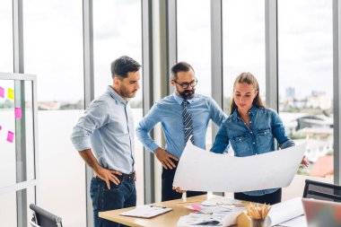 Verileri analiz eden ve yeni başlangıç projesiyle stratejiyi tartışan bir grup profesyonel iş toplantısı. Modern ofiste planlama ve beyin fırtınası yapan yaratıcı iş adamları. Takım çalışması