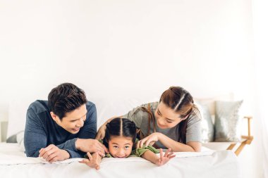 Mutlu gülümseyen bir portre, gülümseyen bir Asyalı aile, anne ve baba ve genç bir aile, küçük bir çocuk, Asyalı kız çocuk, oyun oynuyorlar ve birlikte vakit geçiriyorlar.