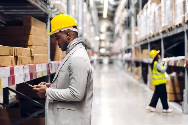 Portrait of smiling african american engineer man order details on tablet checking goods and supplies on shelves with goods background in warehouse.logistic and business export