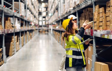 Tablet üzerindeki portre mühendisi kadın nakliyat emri ayrıntıları raflarda malzeme ve malzeme kontrolü fabrika deposunda malzeme envanteriyle birlikte. Lojistik endüstrisi ve iş ihracatı