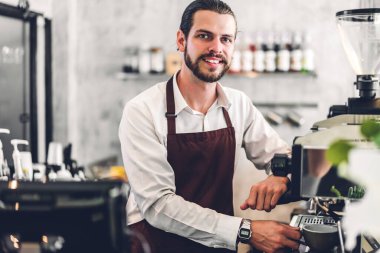 Gülümseme portresi yakışıklı sakallı barista başlangıç küçük işletme sahibi çalışıyor ve kameraya bak bir kafede tezgahın arkasındaki müşteriden sipariş alıyor.